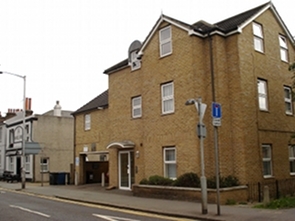 Sign on front of pub reads: “The Wandle Arms”. A fairly new-looking brick building with a gabled roof. Three storeys of windows are visible, though the top storey is in the gables. There's a garage port set into the left side of the ground floor. The Wandle Arms pub is visible to the left, with a few picnic benches outside.